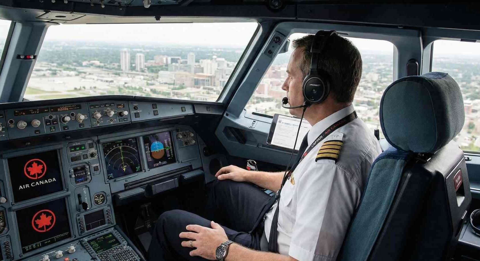 A commercial airline pilot in cockpit with Canadian airline branding